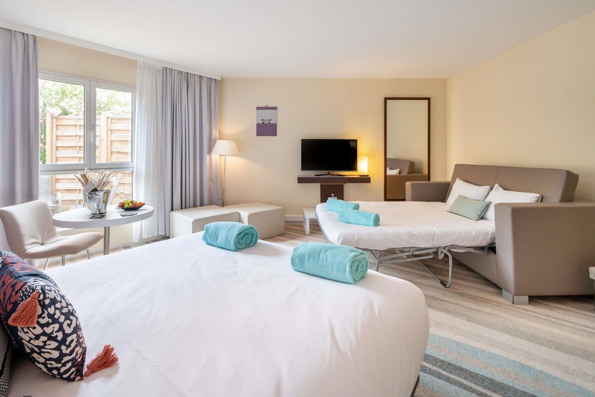 Habitación de hotel con dos camas, televisión, escritorio y silla.