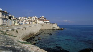 Une ville côtière avec des bâtiments en pierre le long de la mer, un mur de pierre et une eau d’un bleu limpide.