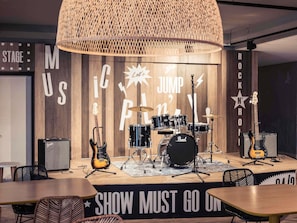A stage with musical instruments, a drum set, and a microphone stand. - Mercure Antibes Sophia Antipolis (Valbonne)