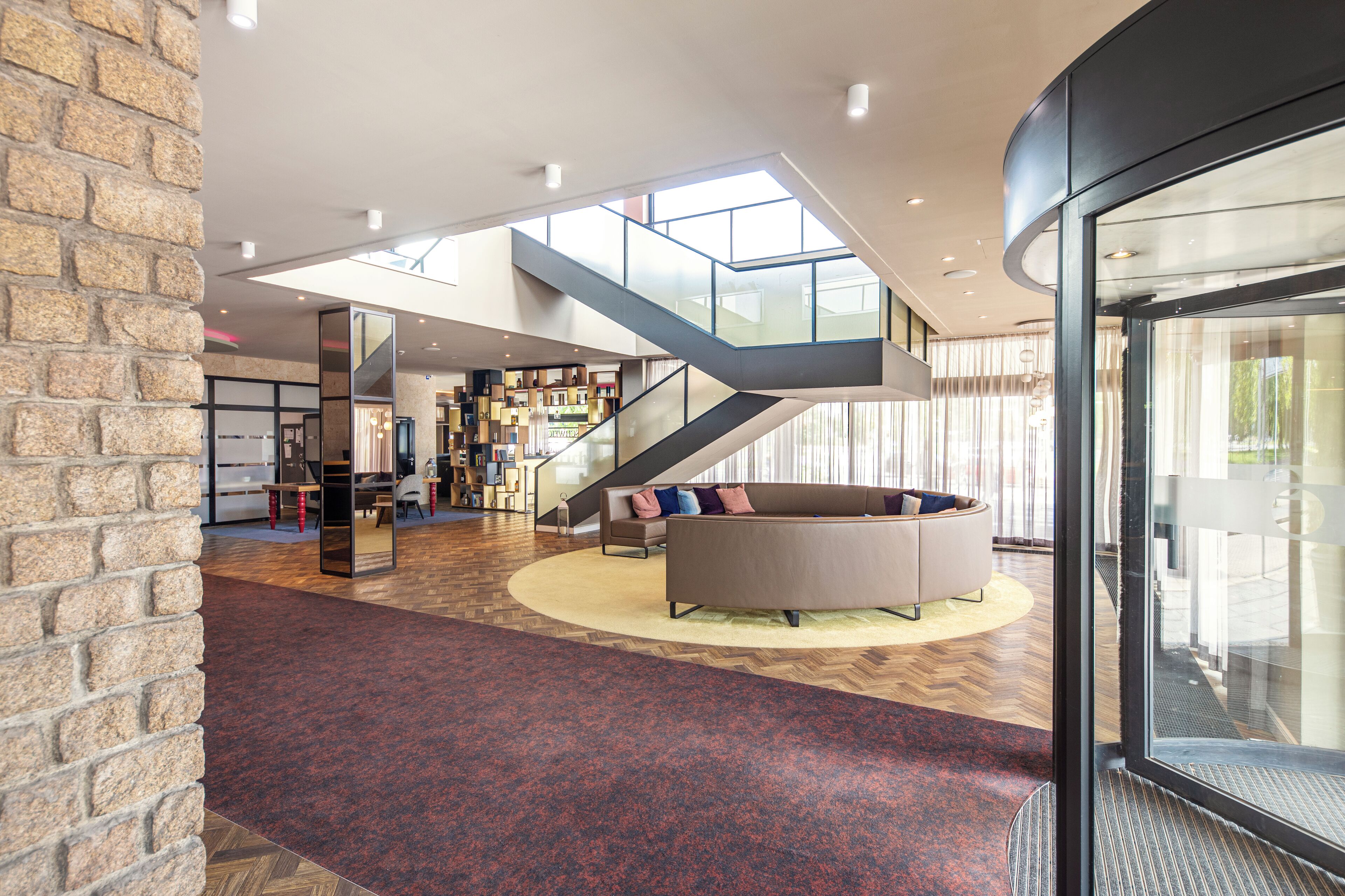 Un hall d’entrée spacieux avec un escalier moderne, un espace salon central et une grande bibliothèque.