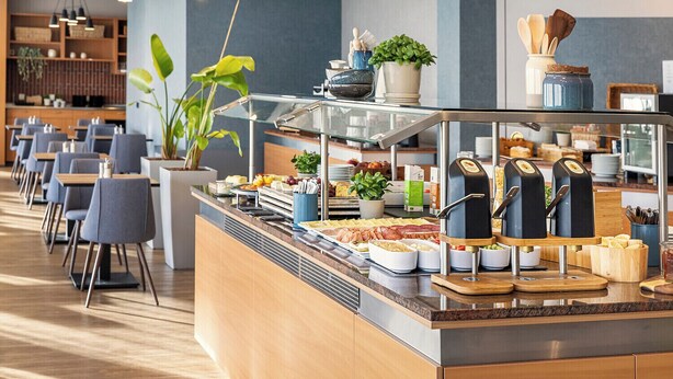 Un espace buffet proposant divers plats, un coin café et des tables où s’asseoir.