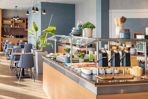 A buffet area with various food items, a coffee station, and seating arrangements. - ACHAT Hotel Braunschweig (Braunschweig)