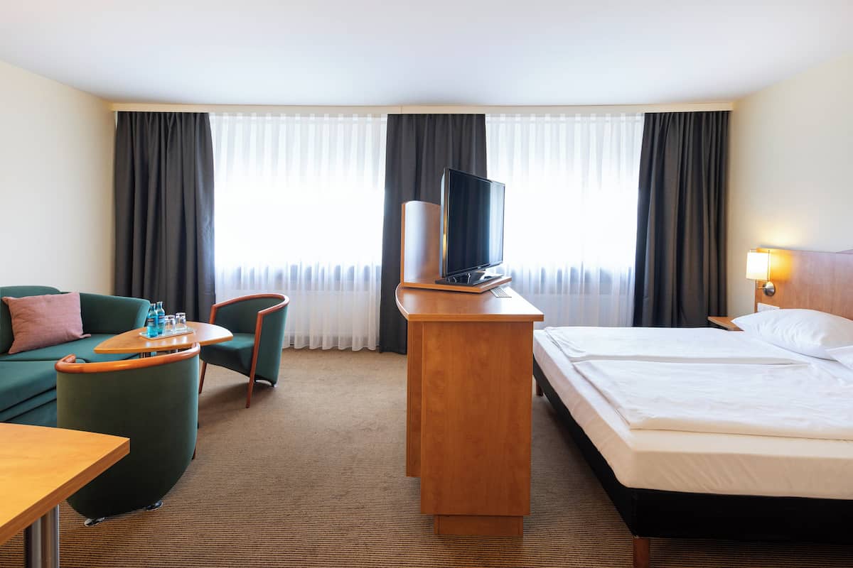 Une chambre d’hôtel comprenant un lit, un bureau, une chaise, un canapé et un téléviseur.