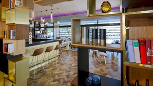 Un intérieur moderne avec un coin bar, des étagères en bois et des livres.