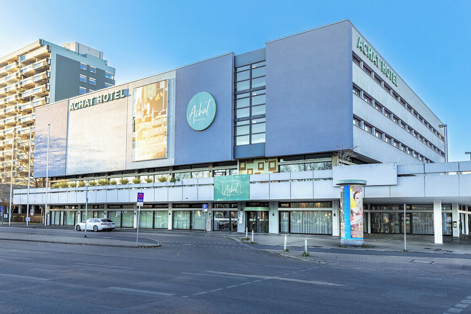 Un hôtel moderne, doté d’une enseigne bien visible, de plusieurs étages et d’un parking.