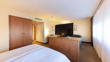 Une chambre d’hôtel comprenant un lit, un bureau avec une télévision et une porte donnant sur une autre pièce.
