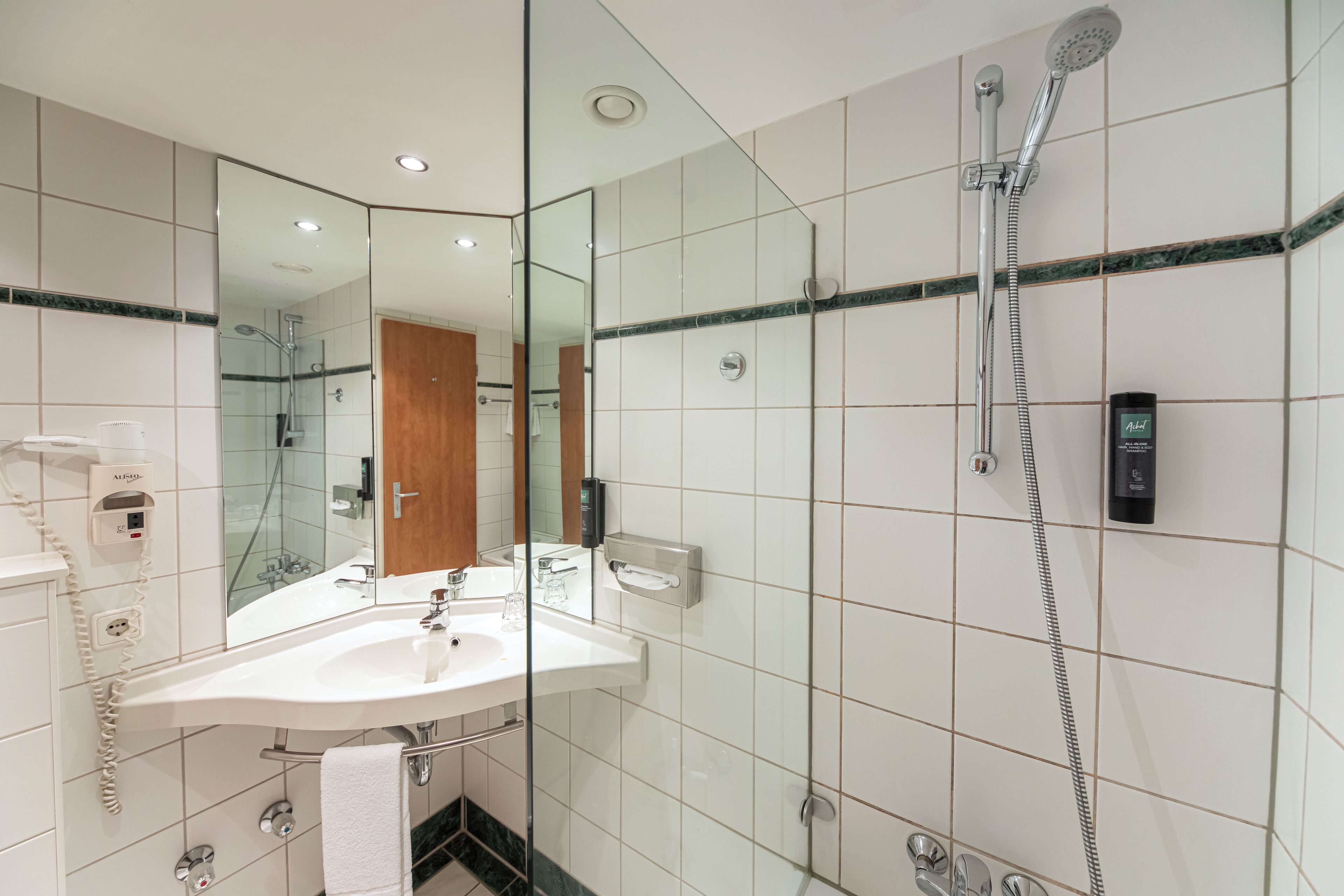 A modern bathroom with a glass-enclosed shower, a white sink, and a mirror.