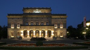 A large, historic building with a central statue, arched windows, and a well-lit entrance. - ACHAT Hotel Braunschweig (Braunschweig)