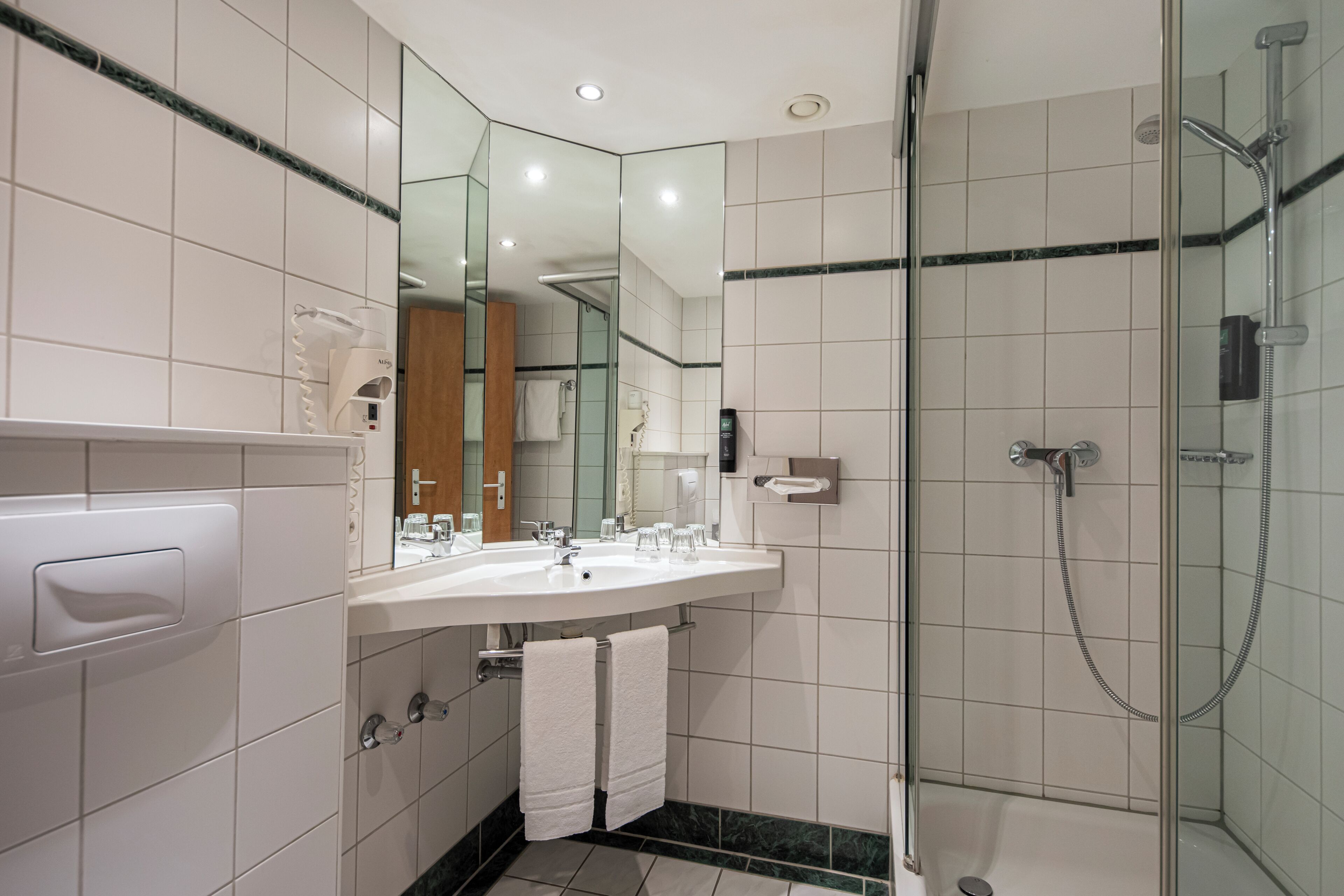 A modern bathroom with a glass-enclosed shower, a white sink, and a mirror.