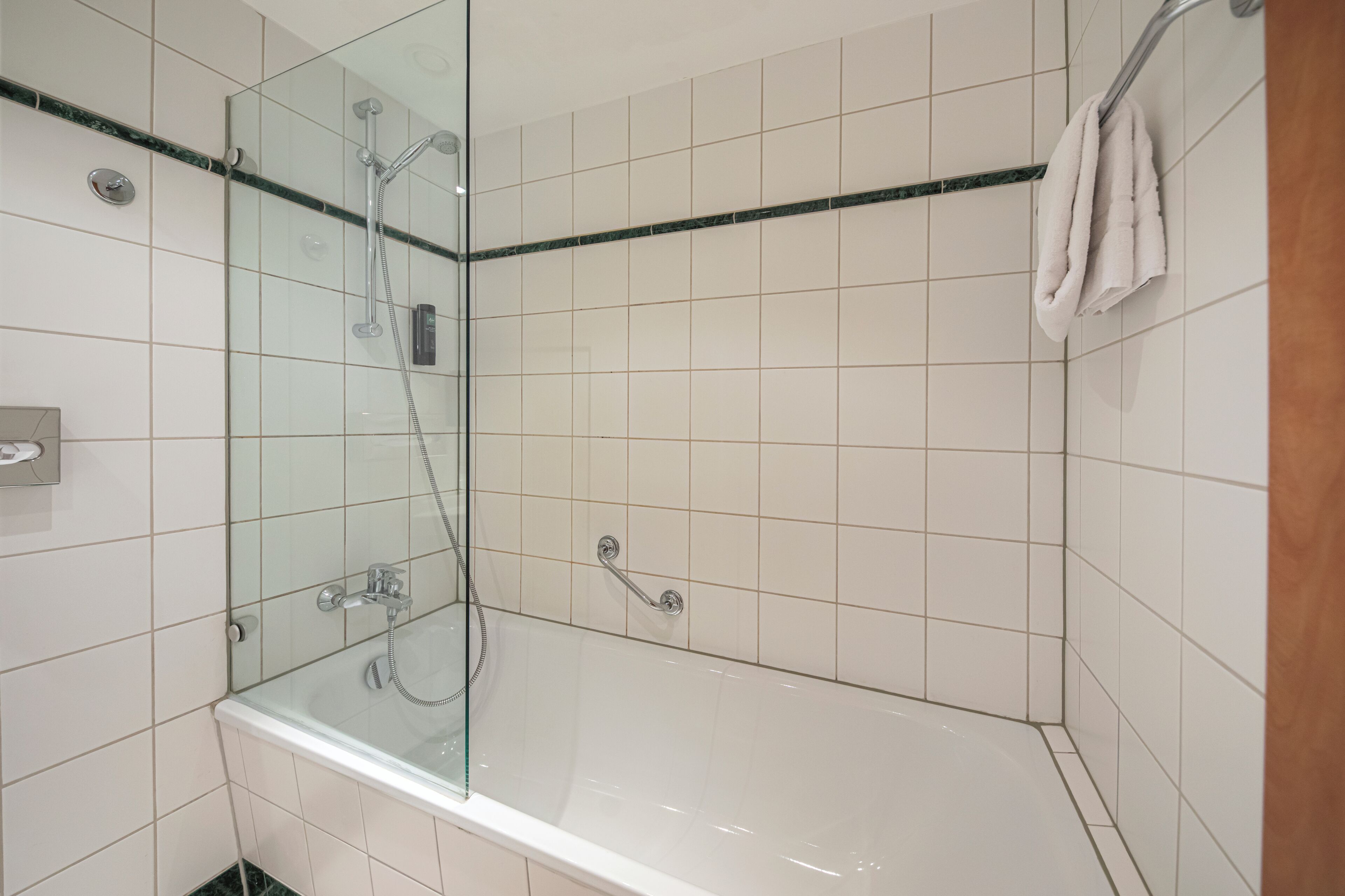 Een moderne badkamer met een douchecabine van glas, een witte badkuip en betegelde wanden.