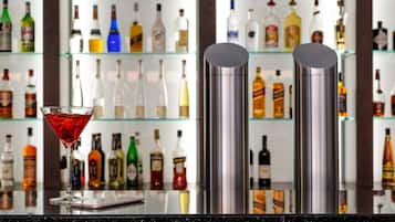 A bar area with a martini glass and two stainless steel shakers on a reflective countertop.