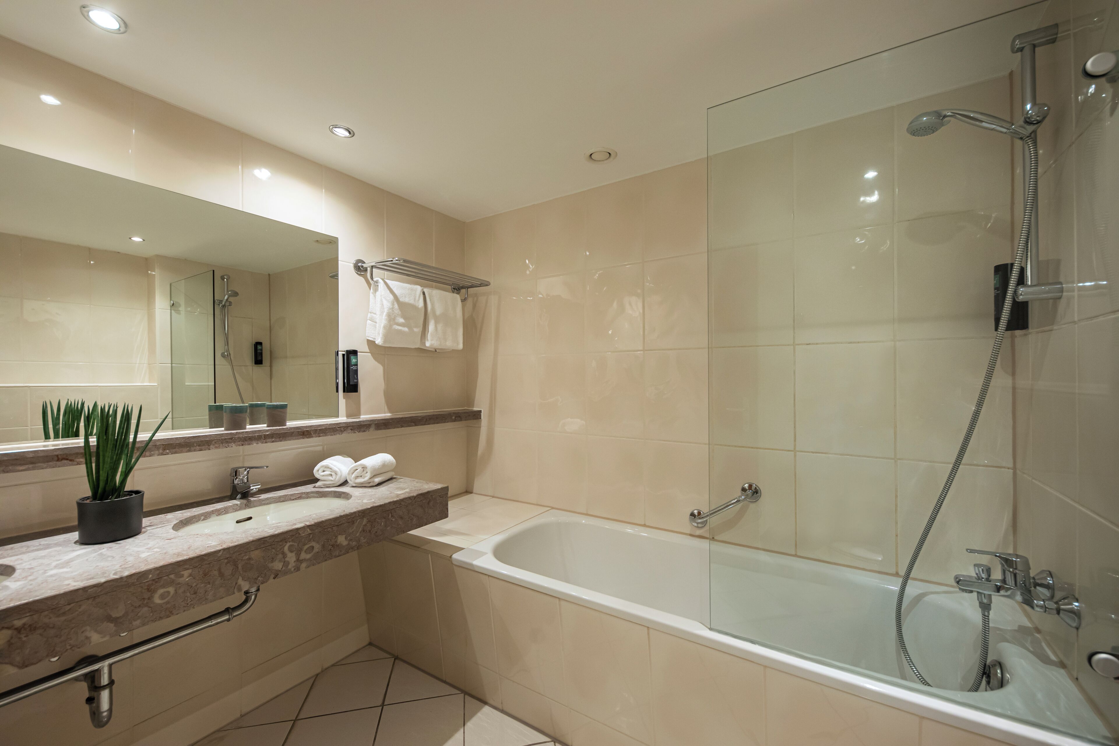 A modern bathroom with a glass-enclosed shower, a freestanding bathtub, and a vanity with a sink and towel rack.