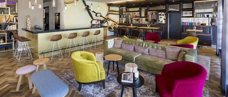 A modern lounge area with a bar, seating arrangements, and a bookshelf.