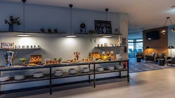 Un café moderne avec un comptoir en marbre, des étagères remplies de produits alimentaires et un espace salon avec des chaises.