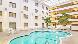 An indoor swimming pool with a modern design, surrounded by lounge chairs and a multi-level building with large windows. - Four Points by Sheraton Bellingham Hotel & Conference Center (Bellingham)