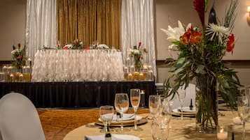 Une table dressée pour un repas, avec des bougies et des arrangements floraux, dans un cadre formel.