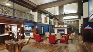 A lobby with a glass coffee table, red armchairs, a fireplace, and a staircase. - Four Points by Sheraton Bellingham Hotel & Conference Center (Bellingham)