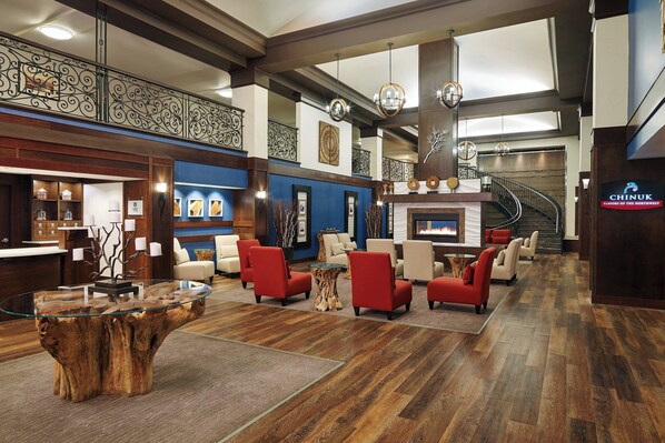 A lobby with a glass coffee table, red armchairs, a fireplace, and a staircase. - Four Points by Sheraton Bellingham Hotel & Conference Center (Bellingham)