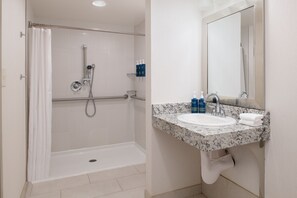 A modern bathroom with a shower, grab bar, sink, and mirror. - Four Points by Sheraton Bellingham Hotel & Conference Center (Bellingham)