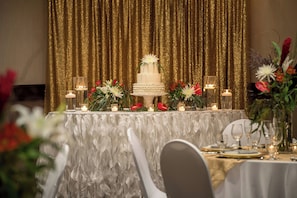 A banquet table with a tiered white cake, floral arrangements, and candles.