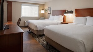 A hotel room with two beds, a desk, a TV, and a window with blinds. - Four Points by Sheraton Bellingham Hotel & Conference Center (Bellingham)