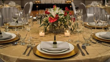 Mesa dispuesta para un evento formal, con una botella de champán, velas y centros de mesa florales.