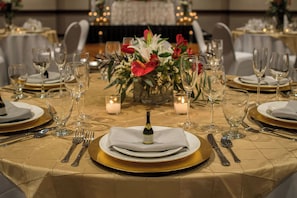 A table set for a formal event with a bottle of champagne, candles, and floral centerpieces.