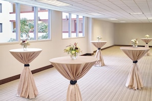 A hotel room with multiple round tables, each with a tablecloth and a vase of flowers. - Four Points by Sheraton Bellingham Hotel & Conference Center (Bellingham)