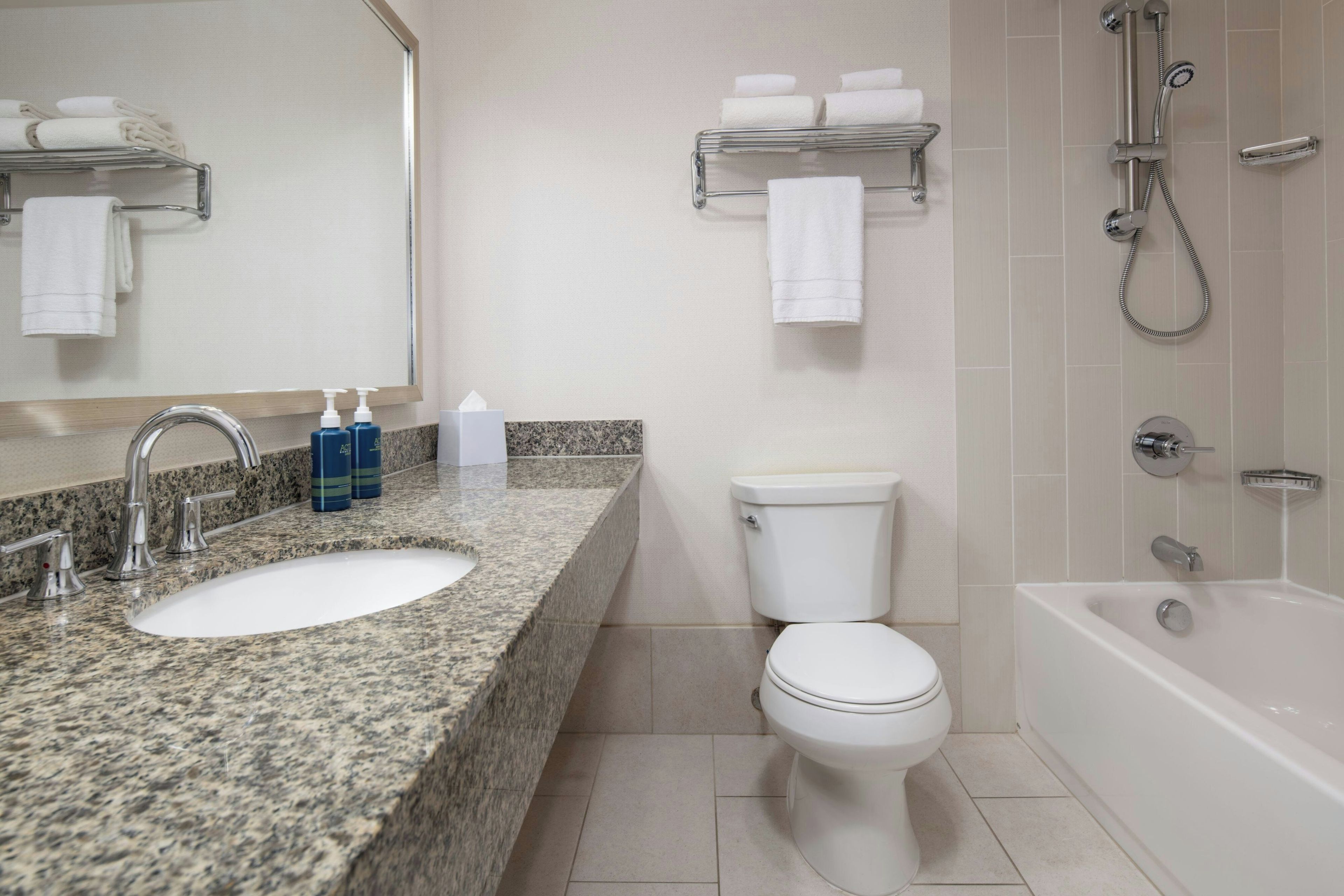A bathroom with a granite countertop sink, a toilet, a bathtub, and a shower.