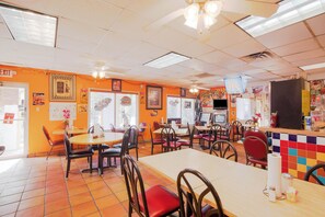 A restaurant interior with multiple tables and chairs, a counter, and a ceiling fan. - Hotel O Grand Inn Channelview I-10 (Channelview)