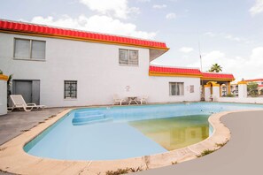 Une piscine avec, en arrière-plan, un bâtiment dont le toit est rouge.