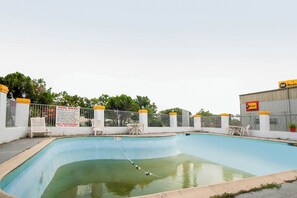 A swimming pool with a pool rule sign, white chairs, and a fence. - Hotel O Grand Inn Channelview I-10 (Channelview)