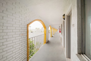 A corridor with white brick walls, yellow arches, and a concrete floor. - Hotel O Grand Inn Channelview I-10 (Channelview)