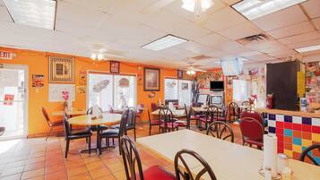 A restaurant interior with multiple tables and chairs, a counter, and a ceiling fan.