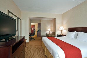 A hotel room with a large bed, a TV on a wooden stand, a desk with a chair, and a lamp. - Holiday Inn Express Hotel & Suites Harriman by IHG (Harriman)