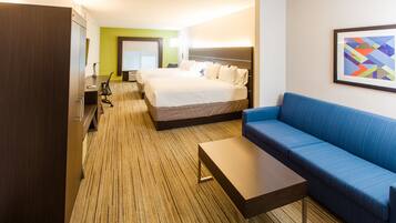 Ein Hotelzimmer mit einem großen Bett, einem blauen Sofa, einem Holztisch und einem Fernseher.