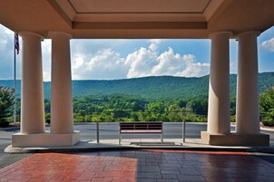 A covered outdoor area with a bench and a view of a forested hill.