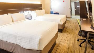 Quarto de hotel com duas camas, uma escrivaninha, uma cadeira e uma televisão.