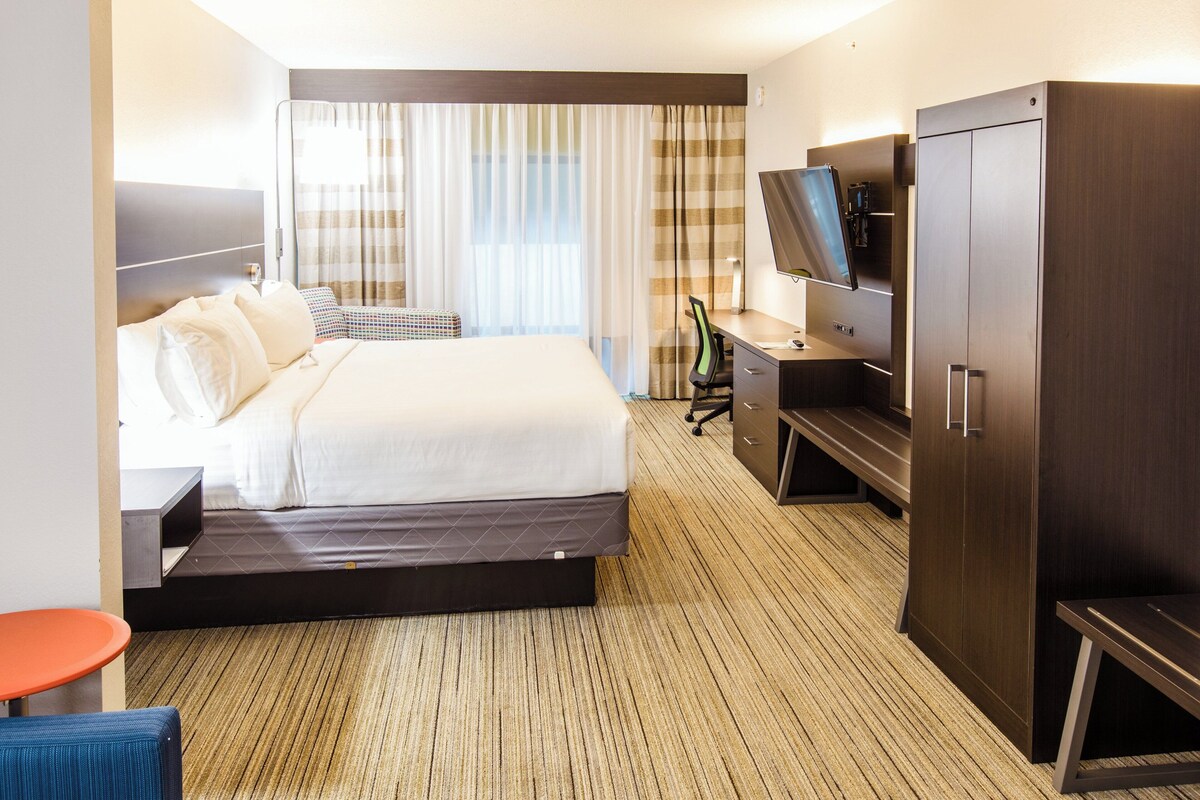 A hotel room with a bed, a desk, a television, and a wardrobe.