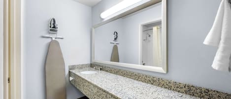 Une salle de bain avec un comptoir en granit, un lavabo blanc, un miroir et une serviette accrochée au mur.