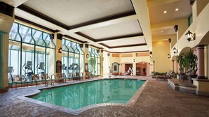 Una piscina interior con sillones de descanso y suelo de piedra.