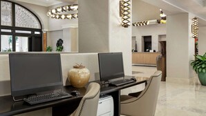 Un espacio de oficina moderno con dos escritorios, cada uno con una computadora y teclado, y un gran jarrón decorativo.