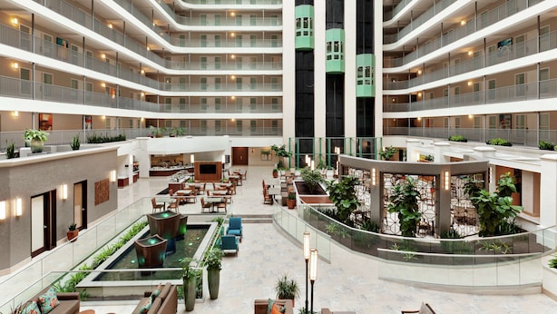 Un vestíbulo de hotel de varios niveles con un patio central, múltiples balcones y zonas de estar interiores.