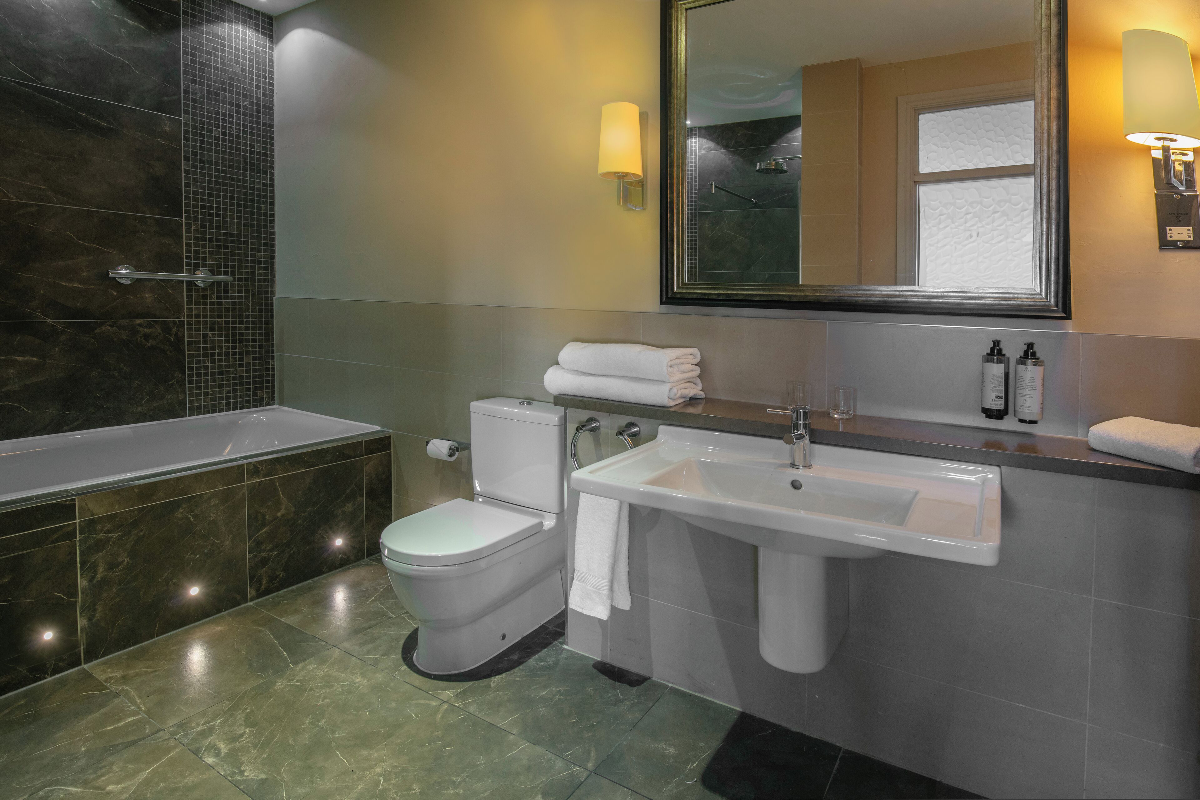 Une salle de bain moderne avec une baignoire, des toilettes, un lavabo et un grand miroir.