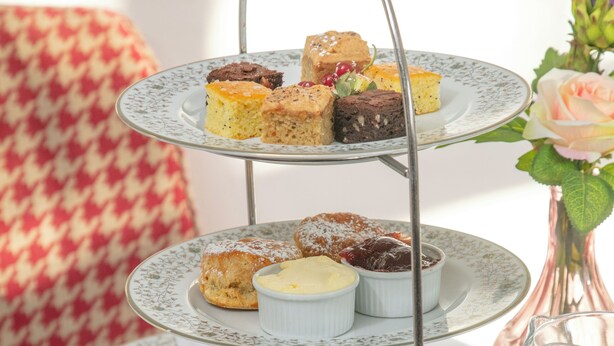 A tiered serving tray with sandwiches, scones, and desserts, accompanied by tea cups and saucers. - Crabwall Manor Hotel & Spa (Chester)