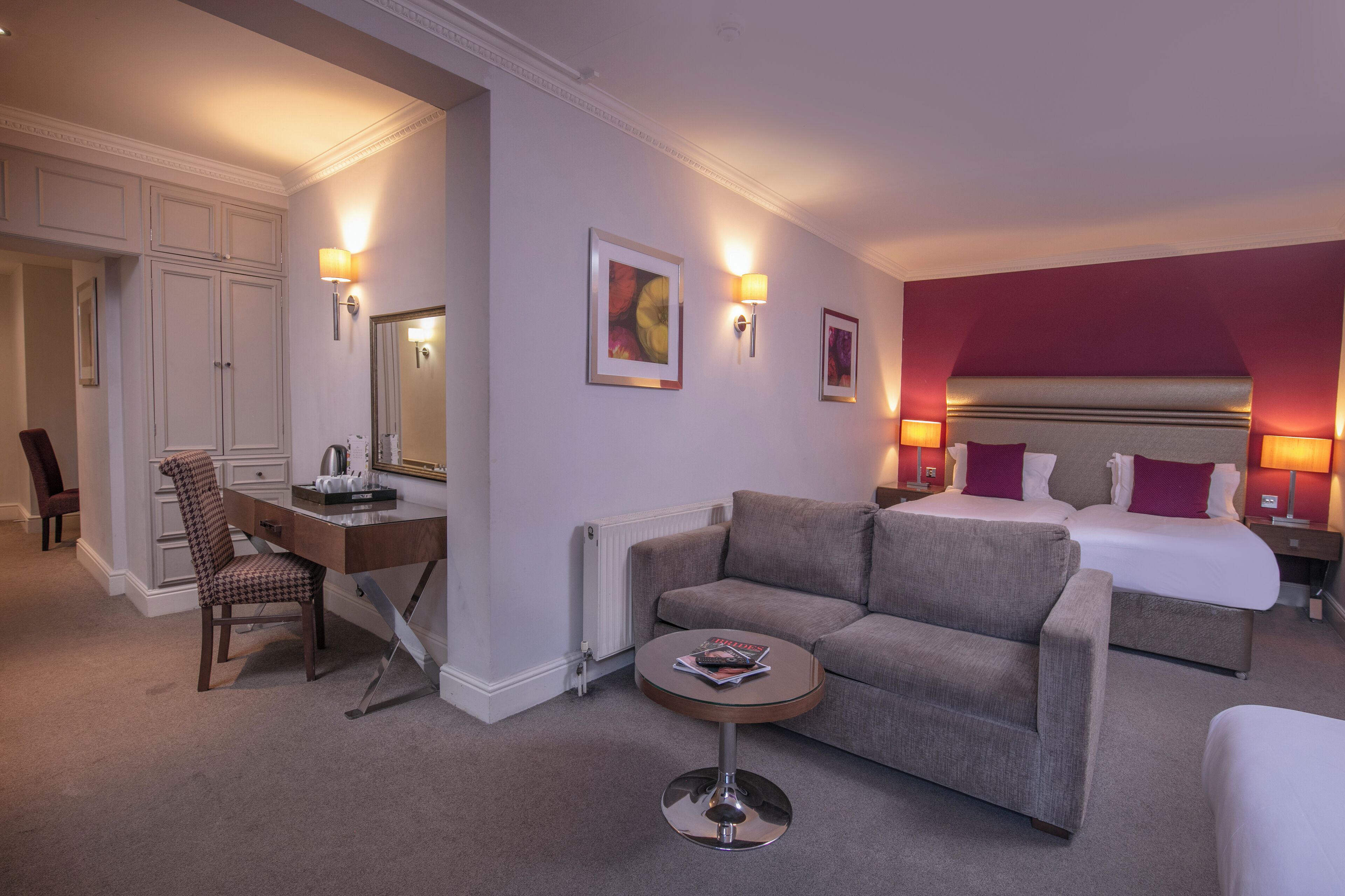 A hotel room with a bed, a sofa, a desk, and a chair.