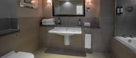 Un baño moderno con un lavamanos blanco, un inodoro, un espejo grande y una zona de ducha.