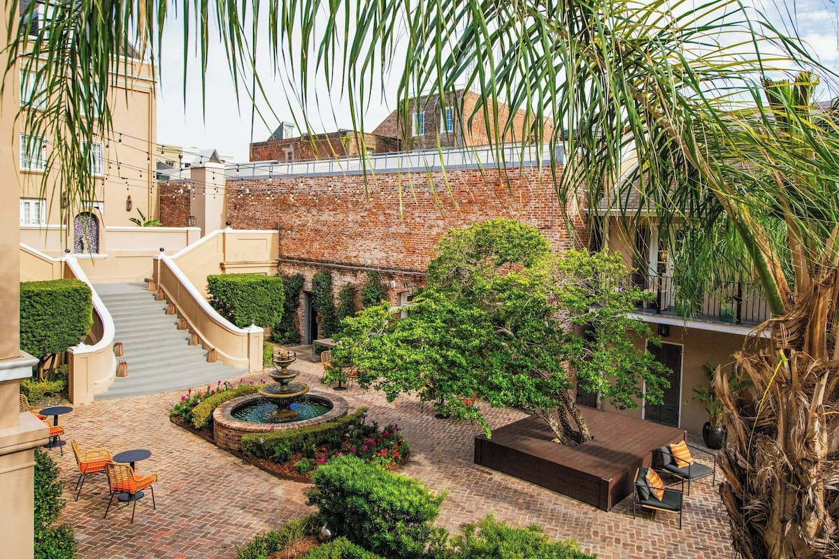 A courtyard with a fountain, seating area, and a staircase leading to an upper level.