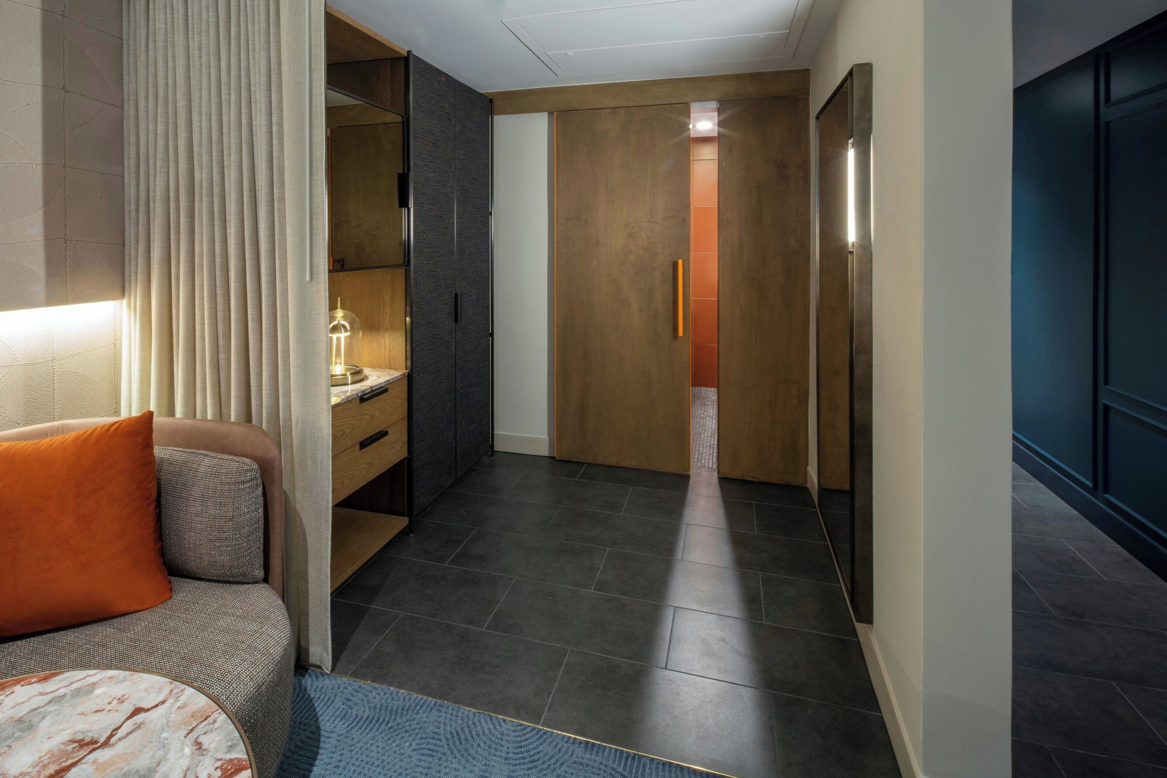Une chambre d’hôtel moderne, équipée d’un canapé, d’une petite table et d’une armoire.