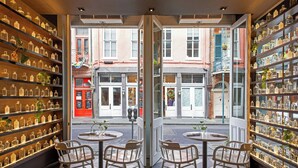 A café with mirrored walls, shelves of glass bottles, and two tables with chairs. - Hotel de la Poste – French Quarter, A Renaissance Hotel (New Orleans)